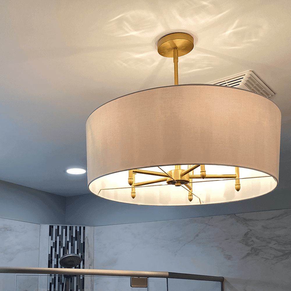 A round overhead light with lampshade hangs in a bathroom.