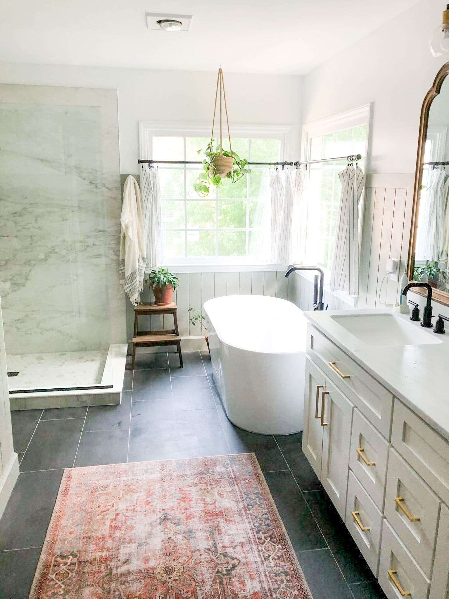 A remodeled bathroom with a walk-in shower on the left and a large oval-shaped white soaking bathtub on the right.