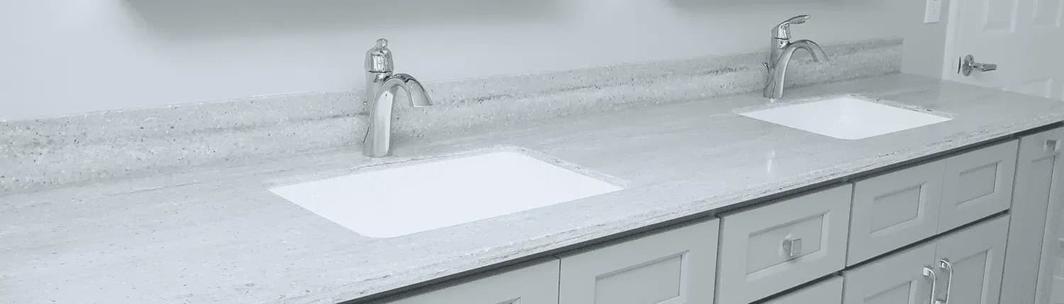 Close-up of a double vanity with gray countertop and gray cabinets.