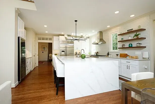A wide kitchen island with a white and gray marbled countertop.