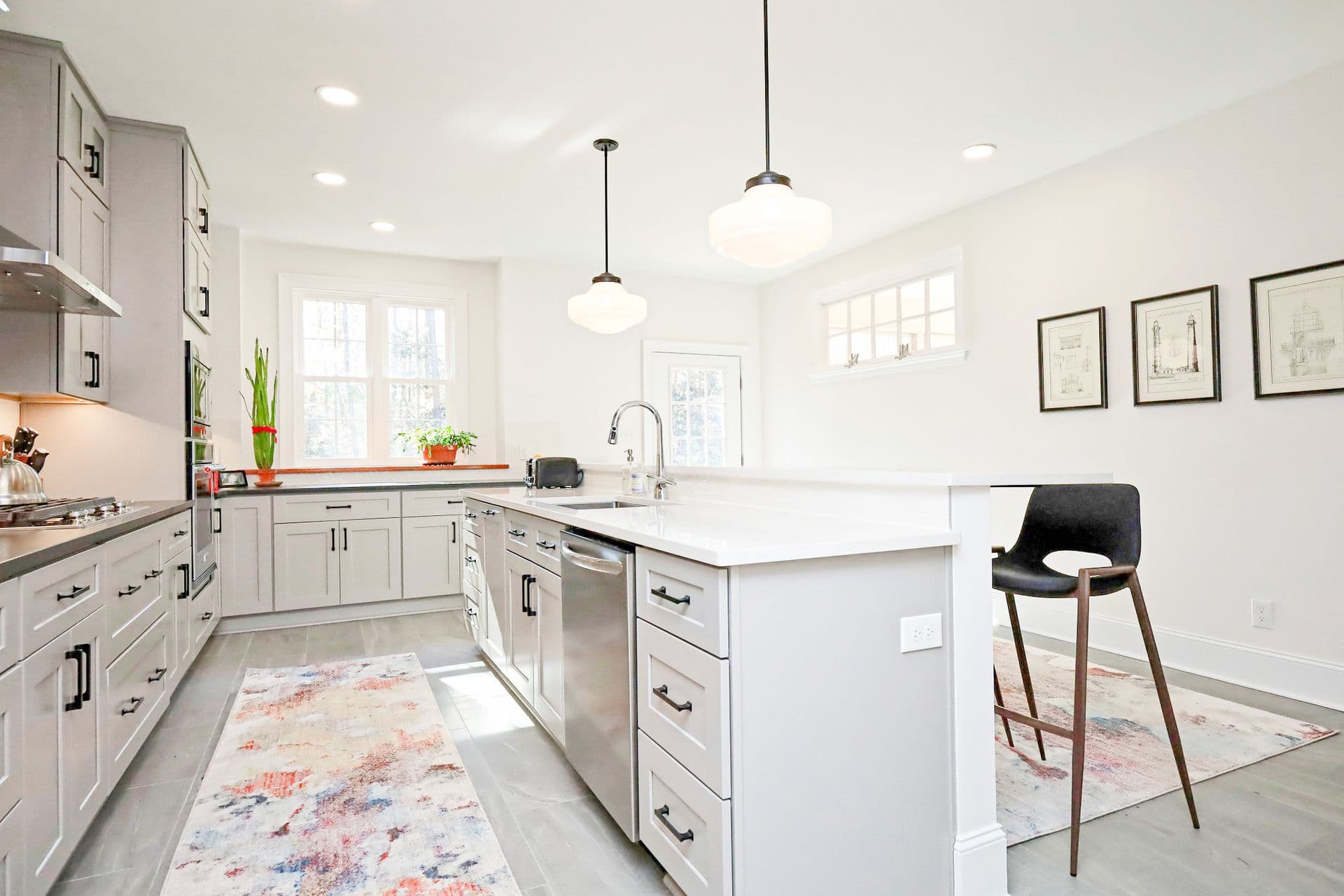 A white kitchen with light gray cabinets and white countertops, and bar stool seating.